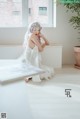 A woman in a white dress sitting on the floor.