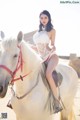 A woman riding on the back of a white horse.