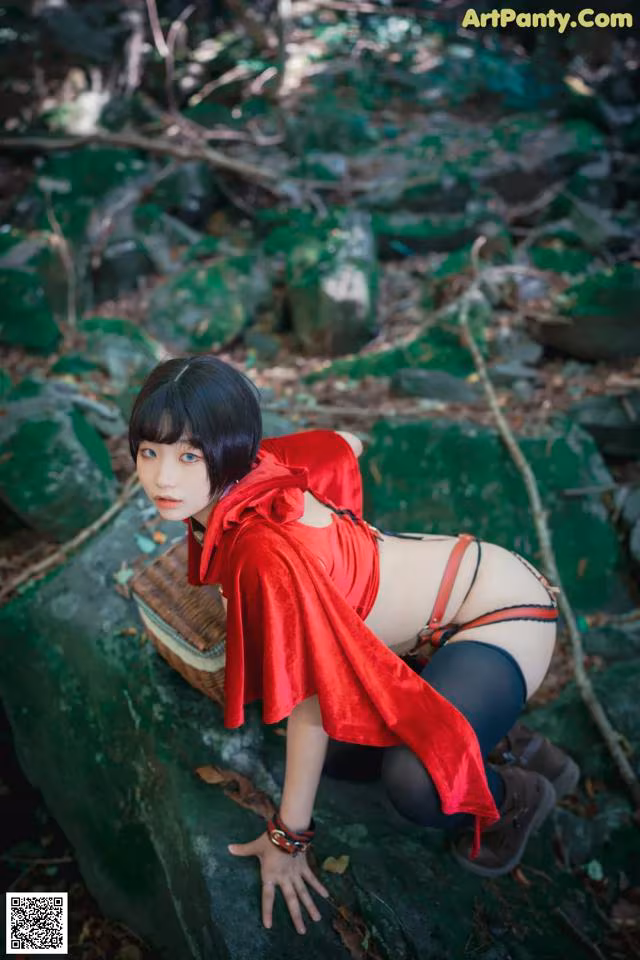 A woman in a red dress is posing on a rock.