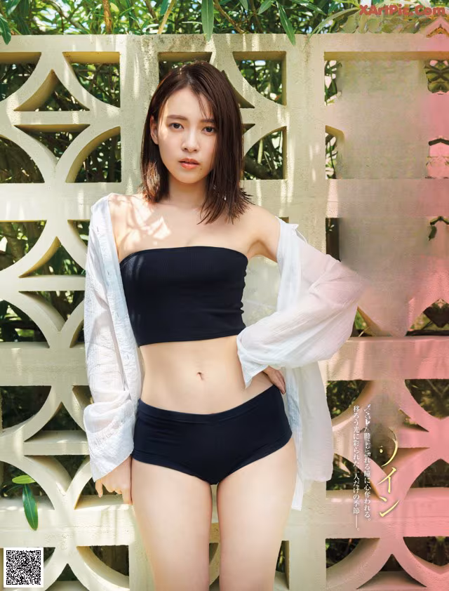 A woman in a black bikini top and black panties posing for a magazine cover.