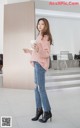 a woman in a pink sweater and jeans holding a cup of coffee