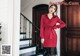 a woman standing in front of a door wearing a red shirt dress