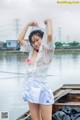 A woman in a white top and blue skirt posing on a boat.