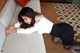 A woman in a white shirt and black skirt laying on a couch.