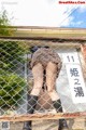 A woman in a school uniform is leaning against a fence.