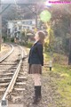 A woman in a school uniform standing on a train track.