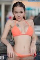 A woman in an orange bikini sitting in a pool.