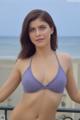 A woman in a purple bikini posing on a balcony.