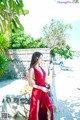 A woman in a red dress standing on a stone wall.