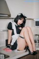 A woman in a maid outfit sitting on a kitchen counter.