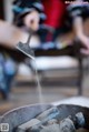 A person pouring water into a metal bowl.