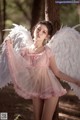 A woman in a pink dress with white angel wings.