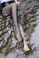 A woman in black stockings is sitting in the water.