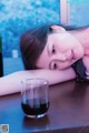 A woman laying on a table next to a glass of wine.