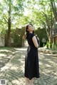 A woman in a black and white polka dot dress standing on a brick walkway.