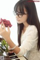 A woman in a white dress holding a red rose.