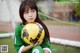 A young girl holding a soccer ball in front of a goal.