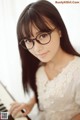 A woman wearing glasses sitting at a piano.