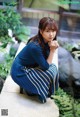 A woman in a blue dress sitting on a stone ledge.