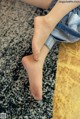 A woman sitting on a rug with her bare feet.