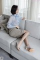 A woman sitting on a couch with her legs crossed.