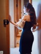 A woman in a black dress standing in front of a door.