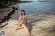 A woman in a bathing suit sitting on the beach.