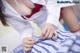 A woman in a white lab coat is putting on a blue and white striped shirt.