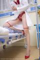 A woman in a white lab coat and red stockings sitting on a hospital bed.