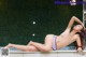 A woman in a bikini laying on the edge of a pool.