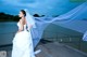 A woman in a wedding dress standing on a dock.