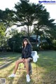 A woman sitting on a chair in a park.