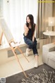 A woman sitting on a chair in front of a drawing board.